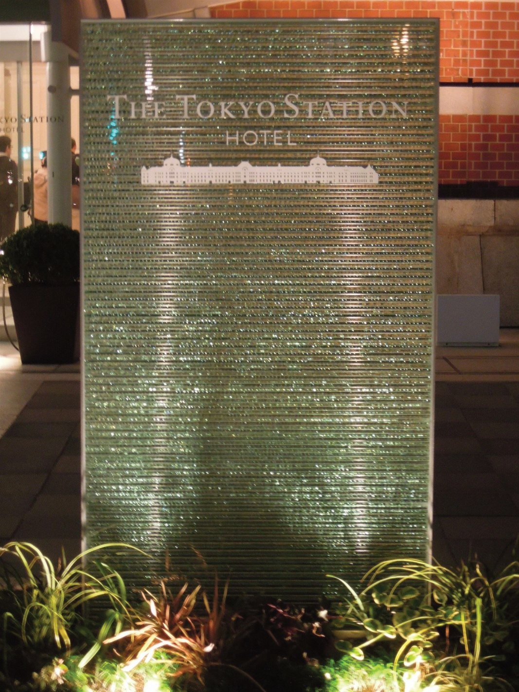 東京ステーションホテル入口サイン。復元された建物全景がデザインされ、さりげなくも印象的なデザインと素材で設えられています。